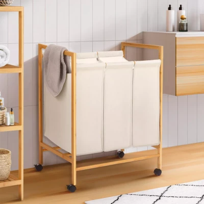 Imagen de IDMarket Cesta de lavandería con 3 compartimentos bambú Rita tela cruda ruedas